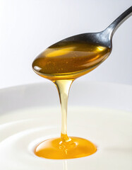 Golden honey drips from spoon into bowl of creamy yogurt, creating delicious and inviting scene