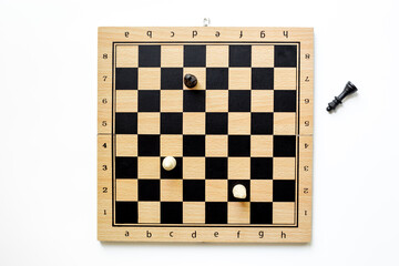 King chess piece lying down near chessboard after checkmate during the game, top view