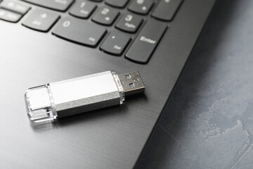 Usb flash drive and laptop on grey textured table, closeup