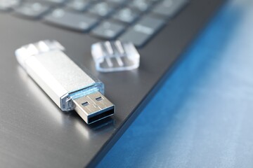 Flash drive and laptop on table, closeup