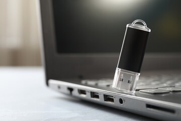 Flash drive and laptop on gray table, closeup