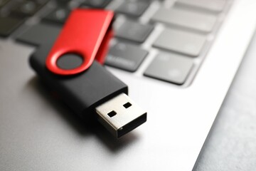 Modern flash drive and laptop on light grey table, closeup