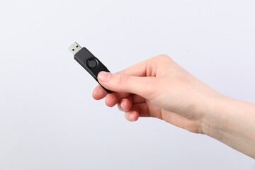 Man with modern flash drive on light grey background, closeup