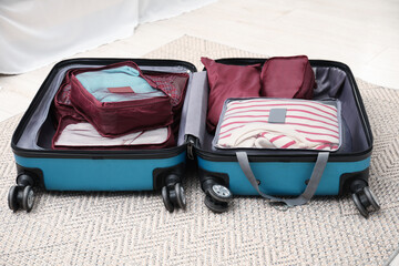 Open suitcase with packing cubes on floor indoors