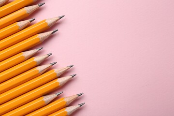 Sharp graphite pencils on pink background, flat lay. Space for text