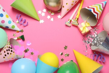 Frame of party hats and festive decor on pink background, flat lay. Space for text