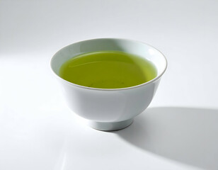 A white ceramic teacup with hot japanese green tea and a slice of lemon is an isolated healthy breakfast drink