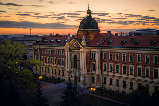 Illuminated facade of Economic University in Krakow, Poland at sunrise.