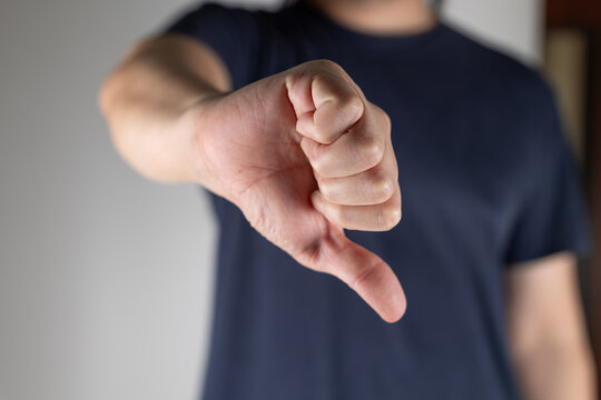 A man makes a thumbs down gesture. A man makes a displeased gesture by pointing his thumb down.
