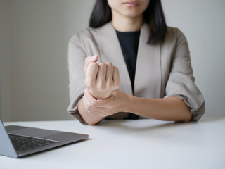 Asian business woman massaging wrist in pain Caused by working on a computer keyboard for a long...