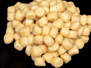 Pile of fresh raw gnocchi, view from above on a black dish