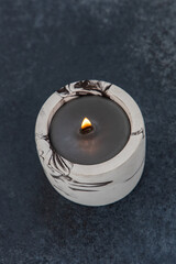 Decorative black candle with flickering flame on dark background