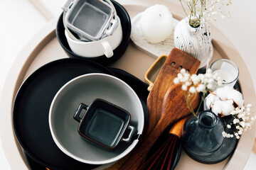 Elegant arrangement of tableware and decor on a wooden tray in bright indoor setting