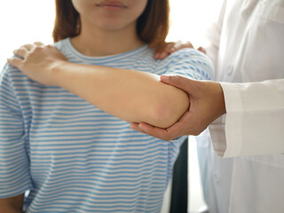 Female physiotherapist assists female patient with elbow injury during checkup in rehabilitation center. Physical therapy concept