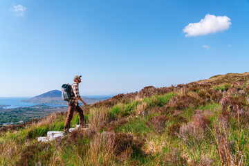 A hiker climbing Diamond Hill  in Connemara National Park, admiring the sweeping views of lakes, mountains, and lush Irish wilderness.