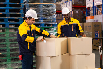 Warehouse technician kneels beside pallet to scan boxes with handheld scanner, checking barcodes...