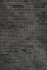 Old gray brick wall made of unevenly laid worn bricks. Retro industrial background.