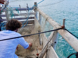 Fishermen emptying their catch from the net on trabucco da Mimi, traditional wooden structure used for fishing in Southern Italy. Peschici, Puglia, Italy,