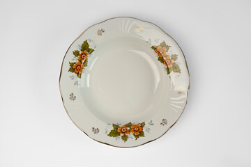 Empty vintage white plate with flowers in plate, isolated on white background. Looking down at a...