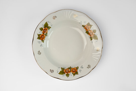 Empty vintage white plate with flowers in plate, isolated on white background. Looking down at a traditional, elegant, white with colorful flower print dinner plate.