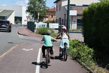 Fototapeta premium Photo of a boy and girl cycling on a bicycle road. Healthy urban lifestyle. Rear view.