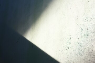 Abstract composition featuring a wall with a textured surface and dramatic interplay of light and shadow. The contrasting areas create a sense of depth and visual interest.