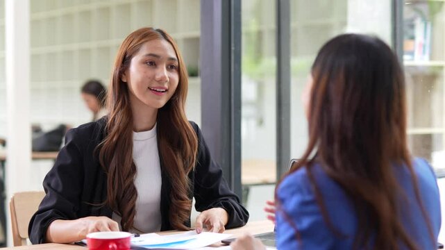 Two Asian businesswomen shaking hands with colleague. Two professional business owners shaking hands to agree to work together in an organization.