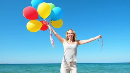 Happy caucasian woman joyfully jumping, holding colorful balloons on a sunny beach with clear blue sky and ocean waves in the background. concept of freedom, happiness, summer fun, seaside joy - Powered by Adobe