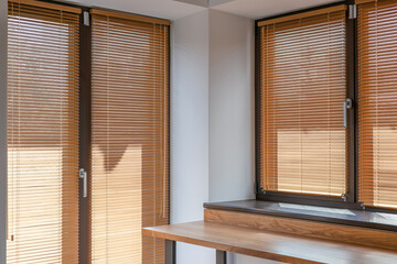 25mm wood blinds cover large windows in sunny room, filtering natural light and providing privacy....
