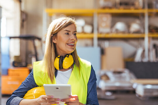 Smiling Female Worker in Warehouse with Safety Gear Using a Digital Tablet
