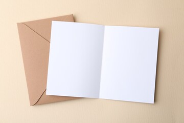 Blank greeting card and envelope on beige background, top view