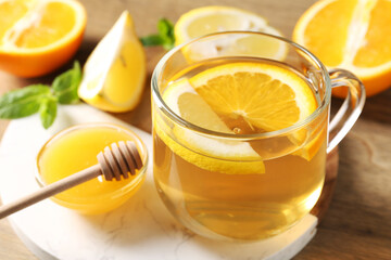 Aromatic fruit tea in glass cup, orange, lemon, honey and mint on table, closeup
