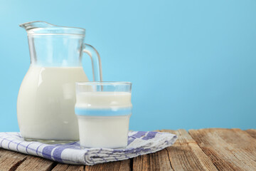 Fresh milk on wooden table against light blue background, closeup. Space for text