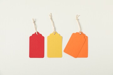 Blank tags with strings on white background, flat lay
