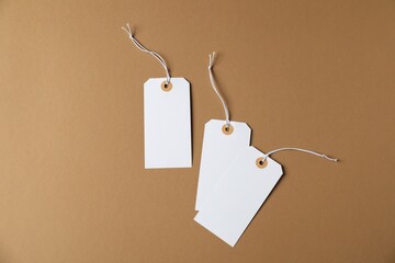 Blank tags with strings on brown background, flat lay