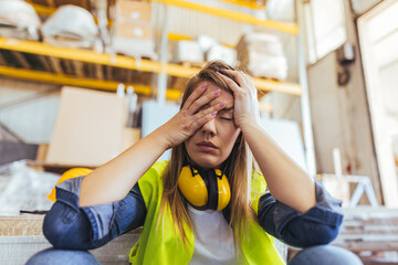 Stressed Female Worker Wearing Safety Gear in Warehouse Environment
