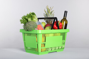 Shopping basket with different food products on gray background