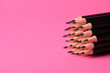 Many sharp graphite pencil on pink background, closeup. Space for text