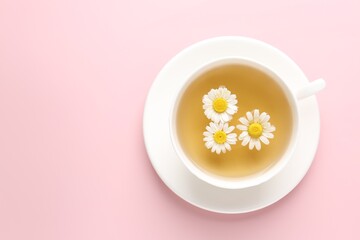 Delicious chamomile tea in cup and fresh flowers on pink background, flat lay. Space for text