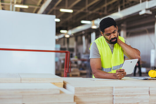 Worker in High Visibility Vest Using Tablet in Industrial Facility