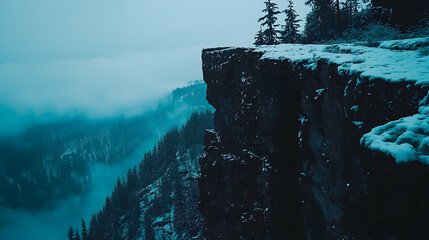 Snowy mountain cliff edge overlooking misty forest.  Possible use nature background