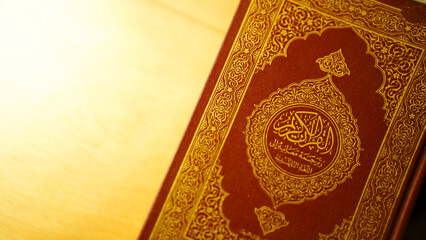 Close up of Quran cover with intricate gold Arabic calligraphy on brown leather symbolizing Islamic...