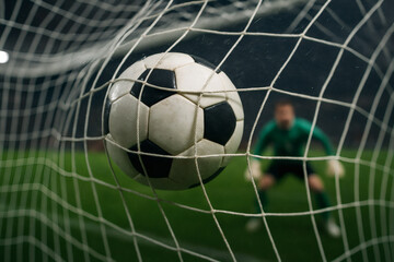 Fototapeta premium Close-Up of Soccer Ball Hitting Net with Goalie Behind