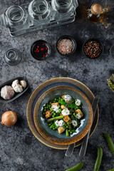 Delicious vegan salad with asparagus, peas, fried tofu and spices on a dark background