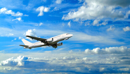 White airplane flying in the blue sky among colorful clouds, air travel background with flying airplane