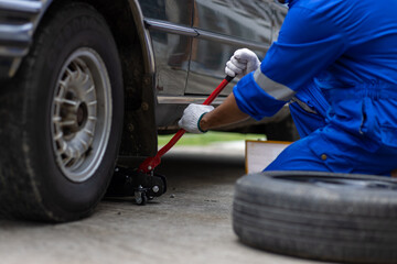 Obraz premium Car mechanic using jack to lift car.