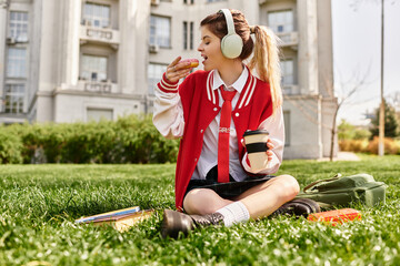 Stylish college girl enjoys snack while relaxing on campus lawn