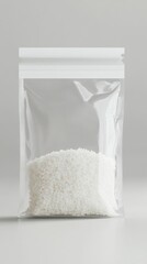 Obraz premium Transparent resealable plastic bag containing white granular material on a plain neutral background perfect for packaging or product display purposes
