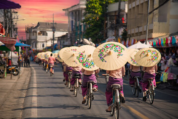Women holding beautiful umbrellas and cycling. show at Bosang umbrella festival Chiang Mai, Thailand.