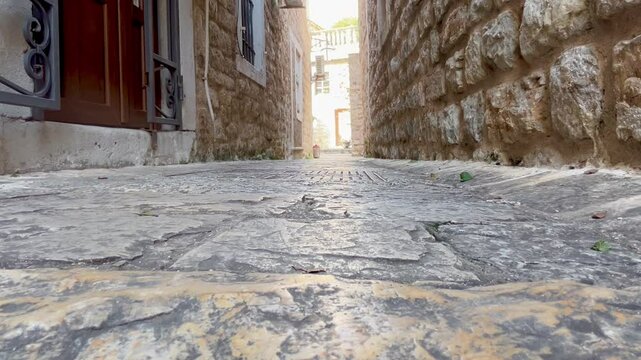 Low angle view of narrow cobblestone street between old stone buildings in Budva